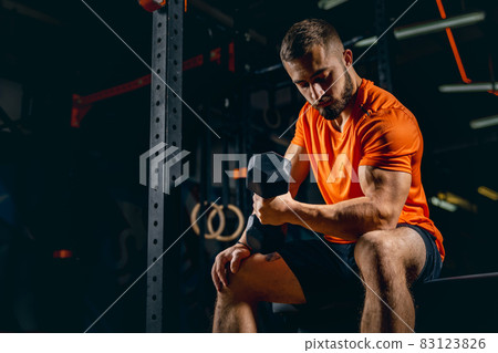 Cropped portrait of young sportive man training, pumping hands with dumbbells in gym Cropped portrait of young sportive man training, pumping hands with dumbbells in gym 83123826