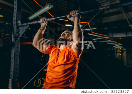 Cropping portrait of young sportive man training in gym and doing pull-ups. Developing strength Cropping portrait of young sportive man training in gym and doing pull-ups. Developing strength 83123837