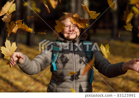 Adult mature fall woman throw up autumn leaves outside in colorful fall forest. Adult mature fall woman throw up autumn leaves outside in colorful fall forest. 83123991