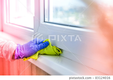Cleaning the windowsill wiping dust by blue microfiber cloth for cleaning on the glass window rail Blue Gloves Cleaning Using Sprayed Liquid. Housework and housekeeping concept. Spring 83124016