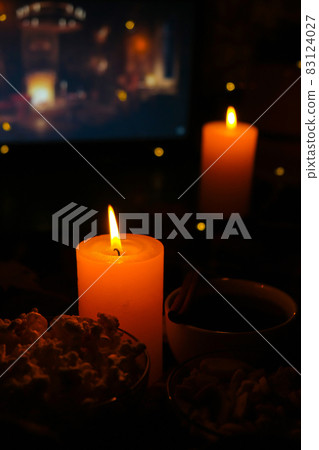 Movie on laptop at night in bedroom lit with candles. Pop corn. Autumn atmosphere at home Movie on laptop at night in bedroom lit with candles. Pop corn. Autumn atmosphere at home 83124027