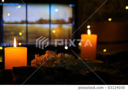 Movie on laptop at night in bedroom lit with candles. Pop corn. Autumn atmosphere at home 83124030