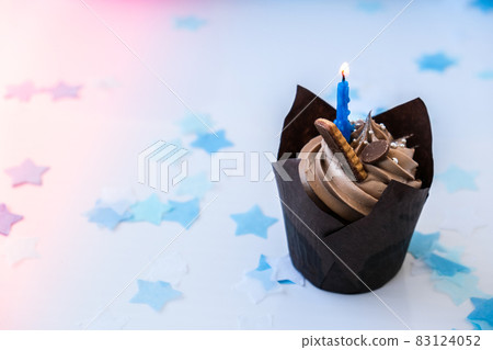 Sweet tasty chocolate cupcake with candle on blue festive background. Happy Birthday party concept. Delicious birthday cake Sweet tasty chocolate cupcake with candle on blue festive background. Happy Birthday party concept. Delicious birthday cake 83124052