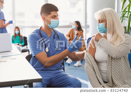Senior Lady Receiving Vaccine Injection In Arm In Medical Centre Senior Lady Receiving Vaccine Injection In Arm In Medical Centre 83124740