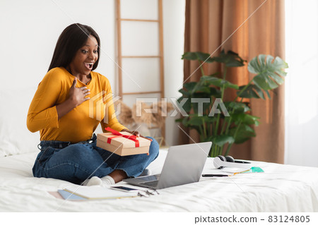 Black Female Video Calling On Laptop Holding Gift Sitting Indoor Black Female Video Calling On Laptop Holding Gift Sitting Indoor 83124805