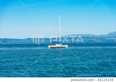 Sailing Boat Moored in front of the Coast of Lake Garda - Lazise village Veneto Italy Sailing Boat Moored in front of the Coast of Lake Garda - Lazise village Veneto Italy 83125219