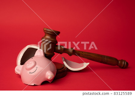 Broken pink piggy bank with wooden judge gavel on a red background. Law and bankruptcy concept 83125589