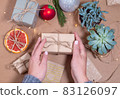 Christmas Gift box wrapped in craft paper in hands of woman 83126097