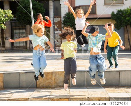 Happy preteen children jumping on city street in summer 83127684