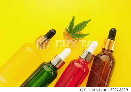 Cannabis cosmetics, cbd oil. Marihuana extract in cosmetology. Flat lay, yellow background. Cannabis cosmetics, cbd oil. Marihuana extract in cosmetology. Flat lay, yellow background. 83128819