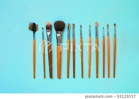 Make up essentials. Set of professional make up brushes on blue background. Make up essentials. Set of professional make up brushes on blue background. 83129157