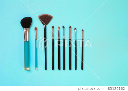 Make up essentials. Set of professional make up brushes on blue background. 83129162