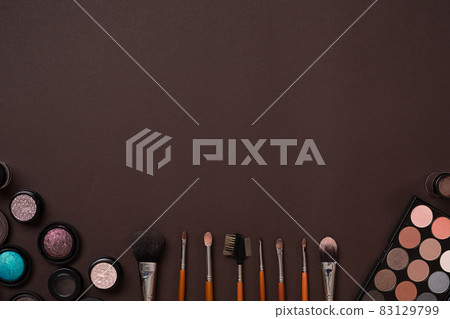 Various cosmetics and brushes on brown background 83129799