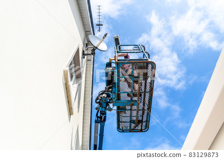 Worker on a aerial access platform, cherry picker, cleaning house Worker on a aerial access platform, cherry picker, cleaning house 83129873