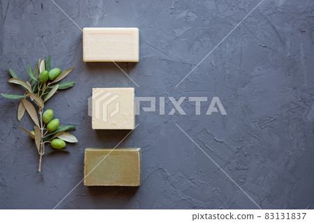 Handmade soap bars and olive branch on grey background, beauty treatment ,top view copy space. 83131837