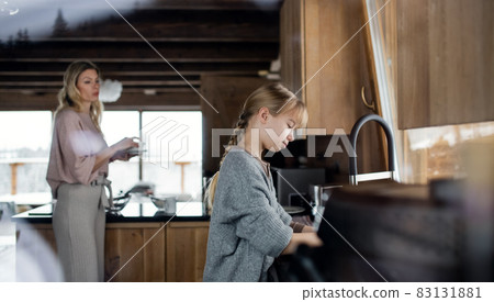 Mother with small daughter washing dishes, winter holiday in private apartment. 83131881