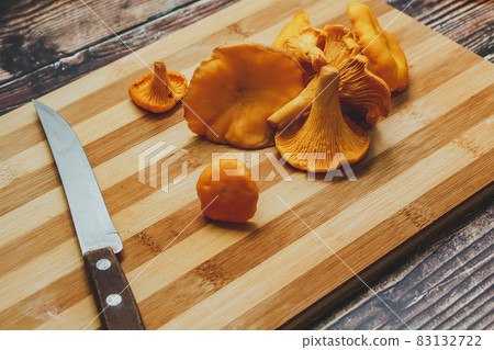 Forest orange chanterelle mushrooms and knife on a wooden board Forest orange chanterelle mushrooms and knife on a wooden board 83132722