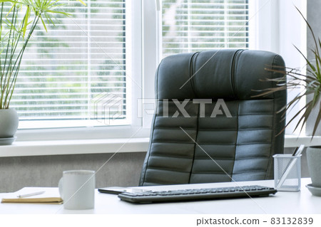 Bright office. Comfortable workplace. Leather chair. Keyboard, notebook and cup of coffee on the desktop. Bright office. Comfortable workplace. Leather chair. Keyboard, notebook and cup of coffee on the desktop. 83132839