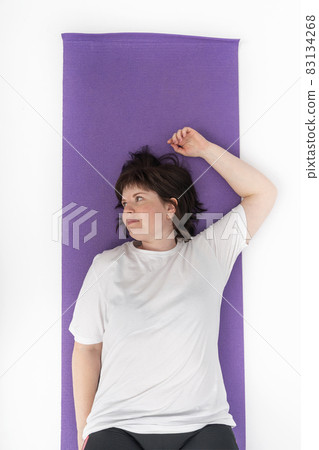 Young plus size woman lies on yoga mat. Girl was tired after sports. Top view. Young plus size woman lies on yoga mat. Girl was tired after sports. Top view. 83134268