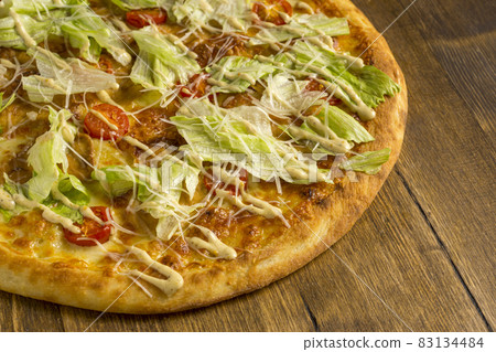 Pizza with cheese, lettuce and cherry tomatoes on wooden background Pizza with cheese, lettuce and cherry tomatoes on wooden background 83134484