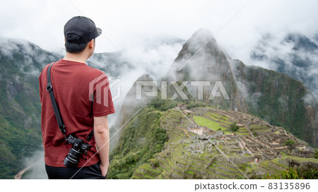 Young Asian man traveler looking at Machu Picchu Young Asian man traveler looking at Machu Picchu 83135896