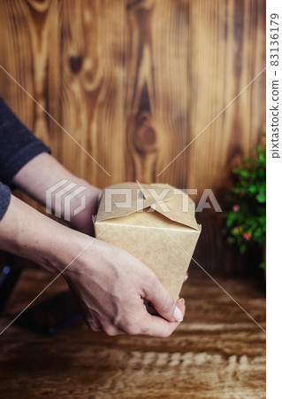 Food delivery. The girl holds paper bags with fast food in her hands. The concept of countering covid 19. Delivery from a restaurant or cafe. Unpacking meal containers Food delivery. The girl holds paper bags with fast food in her hands. The concept of countering covid 19. Delivery from a restaurant or cafe. Unpacking meal containers 83136179