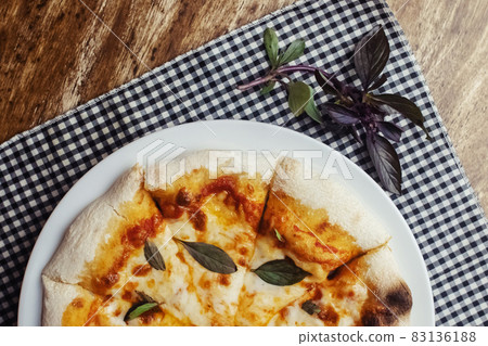 Close-up of Margarita pizza in a disposable dish. Top view of takeaway food in a fast food cafe. On photo - mozzarella cheese, tomatoes, and red basil. The classic recipe. Food for family and friends. Close-up of Margarita pizza in a disposable dish. Top view of takeaway food in a fast food cafe. On photo - mozzarella cheese, tomatoes, and red basil. The classic recipe. Food for family and friends. 83136188