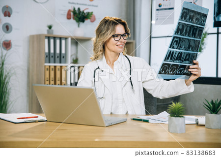 Female doctor examining x ray scan at office Female doctor examining x ray scan at office 83138683