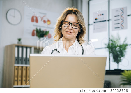 Female medical worker typing on laptop at cabinet 83138708