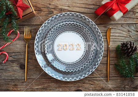 Creative Christmas table setting. Empty plates, numbers 2022, on rustic wooden xmas background. Creative Christmas table setting. Empty plates, numbers 2022, on rustic wooden xmas background. 83141858