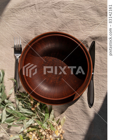 Empty craft handmade clay plate with fork knife on tablecloth. Table place hand crafted dish Natural home interior decor 83142161