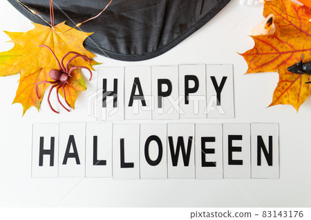 Happy Halloween lettering isolated on white background, holiday and party concept. Against the background of a spider, a mouse, a hat, yellow leaves. 83143176
