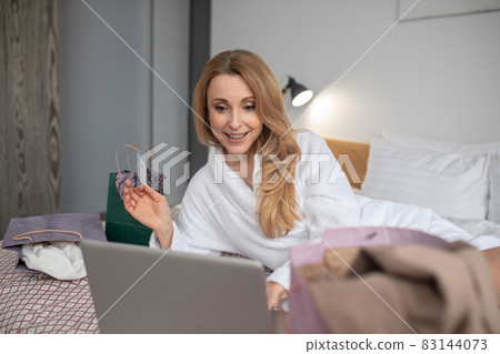 Smiling woman with credit card looking at laptop Smiling woman with credit card looking at laptop 83144073