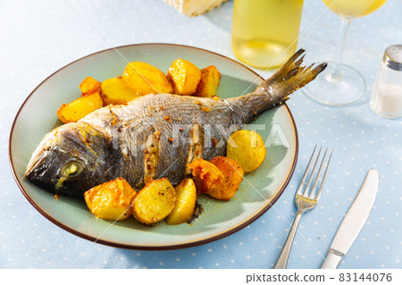 Baked fish called Dorada with toasted potatoes Baked fish called Dorada with toasted potatoes 83144076