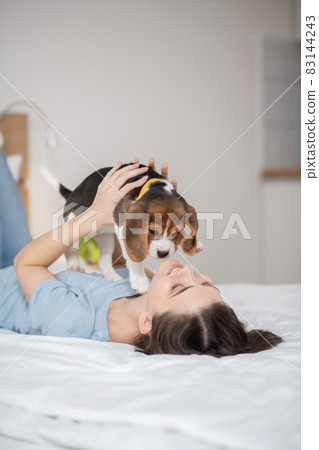 A young woman holding her little cute puppy abd feeling peaceful 83144243