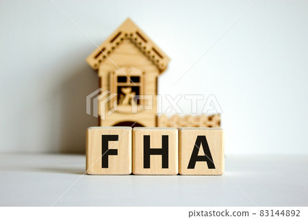 Wooden cubes form the word 'FHA, federal housing administration' near miniature house. Beautiful white background, copy space. business concept. Wooden cubes form the word 'FHA, federal housing administration' near miniature house. Beautiful white background, copy space. business concept. 83144892