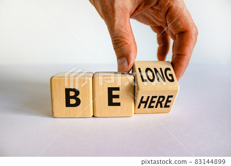 Be here belong symbol. Businessman hand turns a cube and changes words 'be here' to 'belong'. Beautiful white background. Business, belonging and be here belong concept. Copy space. Be here belong symbol. Businessman hand turns a cube and changes words 'be here' to 'belong'. Beautiful white background. Business, belonging and be here belong concept. Copy space. 83144899