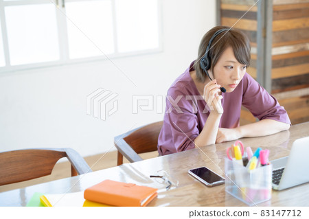 一位年輕女性在遠程辦公期間焦急地看著視頻會議 83147712
