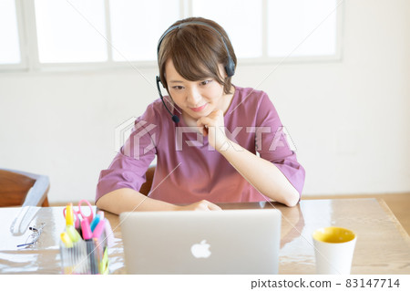 A young woman having a video conference on ZOOM using a laptop during teleworking A young woman having a video conference on ZOOM using a laptop during teleworking 83147714