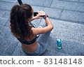 Young athletic woman checking her training results on sport watch while resting on stairs 83148148