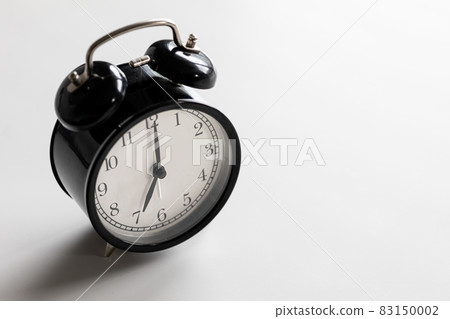 Black and white vintage classic alarm clock at seven o'clock with white space. Black and white vintage classic alarm clock at seven o'clock with white space. 83150002