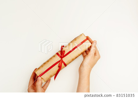 Wrapped Christmas gift in woman hands above white background Wrapped Christmas gift in woman hands above white background 83151035