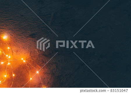 Warm light illuminated garland close up on dark background Warm light illuminated garland close up on dark background 83151047