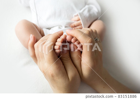 Hands of parents. The legs, feet of the newborn in the hands of mom and dad. 83151886