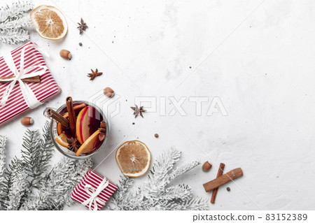 Christmas flat lay top view on white gray concrete background table with Mulled Wine glass cup or mug, present red gift boxes, decorations, cinnamon, orange slices, spices, fir. Christmas time photo 83152389