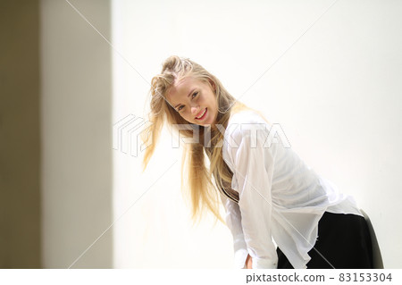 Portrait of young beautiful woman blonde hair standing against wall with copy space 83153304