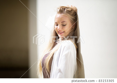 Portrait of young beautiful woman blonde hair standing against wall with copy space Portrait of young beautiful woman blonde hair standing against wall with copy space 83153305