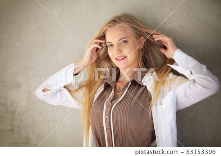 Portrait of young beautiful woman blonde hair standing against wall with copy space Portrait of young beautiful woman blonde hair standing against wall with copy space 83153306