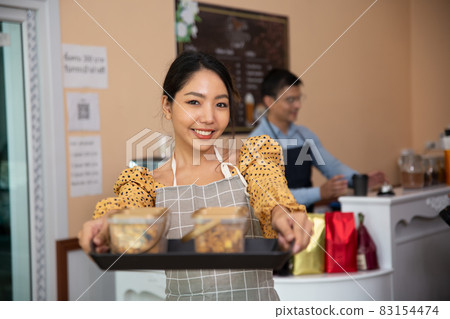 smiling women holding cookies in coffee shop as small business owner. 83154474