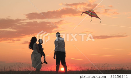mom dad and child fly kite at sunset in sky, happy family, father mother and child travel together, childhood dream, family life, little boy walks with his parents in park sunshine, family silhouette mom dad and child fly kite at sunset in sky, happy family, father mother and child travel together, childhood dream, family life, little boy walks with his parents in park sunshine, family silhouette 83156341
